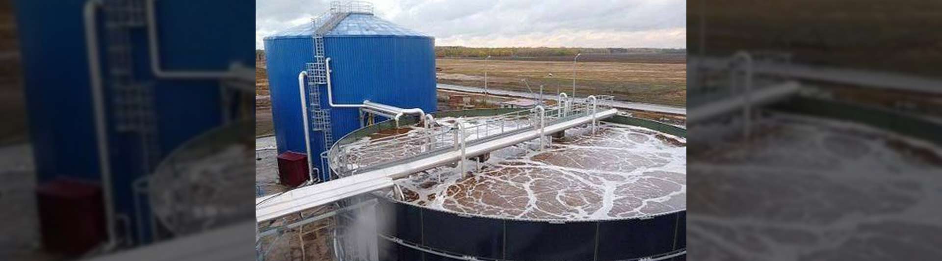 Aerobic tank with foam and blue digester at a biological wastewater treatment facility.