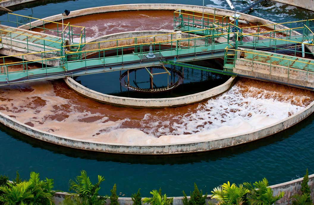 Aerial view of a wastewater treatment plant with circular tanks, walkways, and aeration systems.