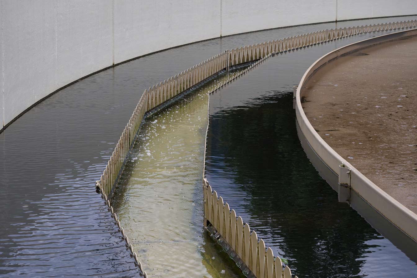 Sewage sludge flowing through a channel in a wastewater treatment plant tank.