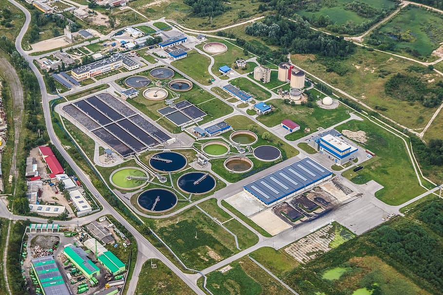 Aerial view of a wastewater treatment plant with circular tanks and green pipes